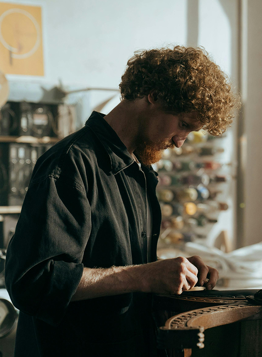 Homme aux cheveux roux et bouclés concentré sur une tâche artisanale