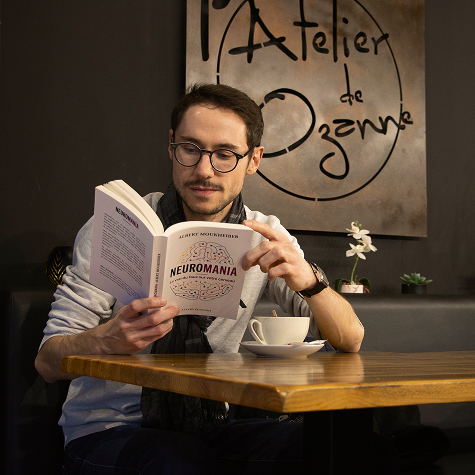Maxime Sciare lisant un livre dans un café
