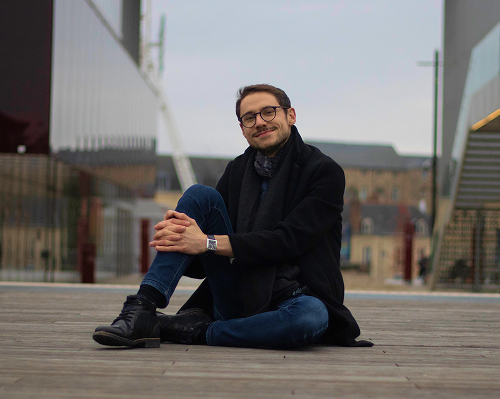 Maxime assis par terre avec un sourire calme